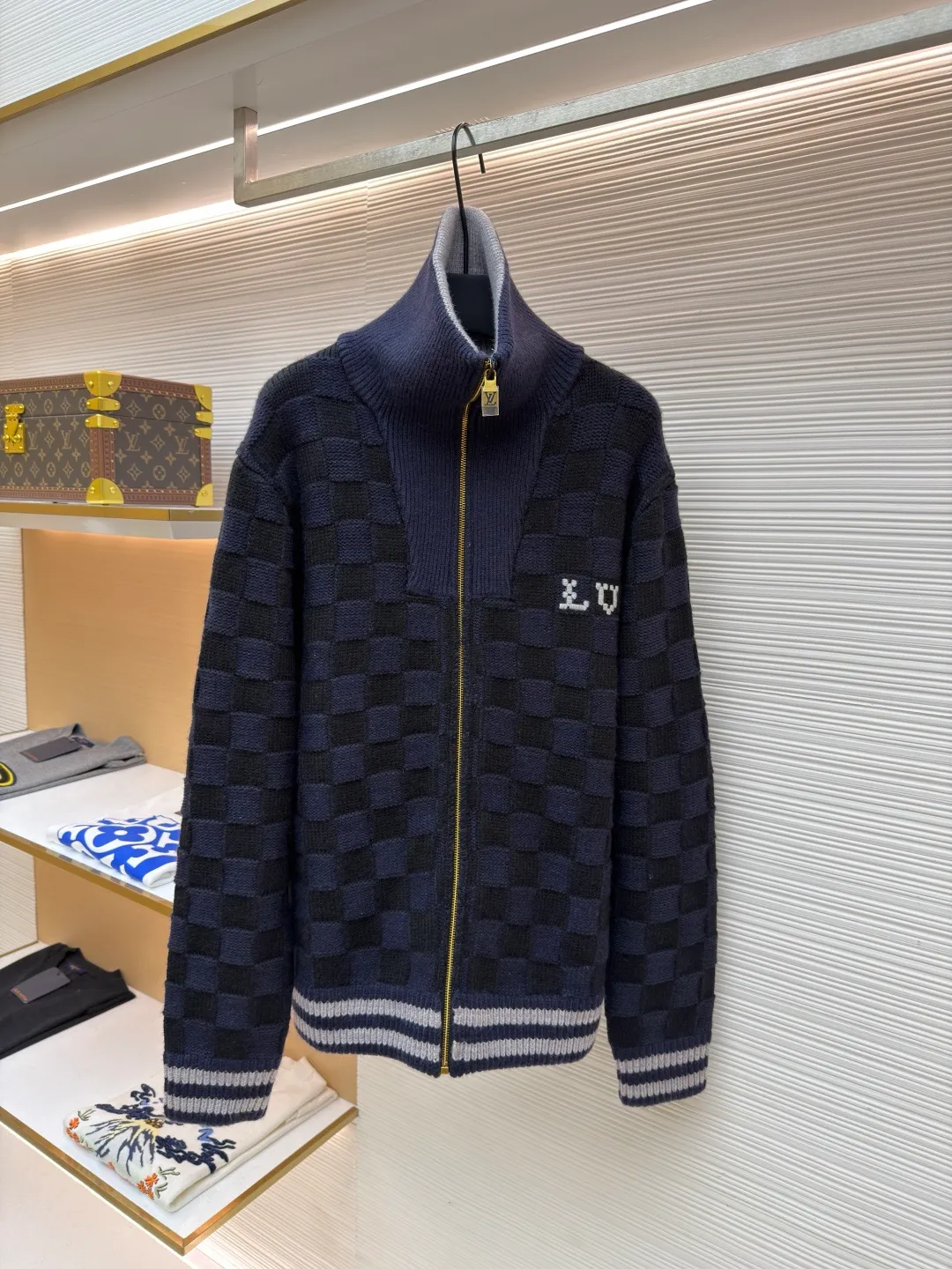 LOUIS VUITTON knitted waist contrast ribbed collar sweater ●Original version: purchased and developed by 20433 ●Item number: 1682136-C10 ●Fabric: wool blended fabric ●Technology: knitted ●Color: black and blue ●Version: fitted version ●Weight: about 1360 grams ●Size: S-M-L-XL ●Description: This Louis Vuitton checkerboard knitted zipper jacket is made of double-ply merino wool blended yarn and is woven with a 12-needle three-dimensional knitting process on a German Stoll computerized flat knitting machine. The Damier checkerboard pattern on the body uses intarsia knitting techniques, and the layered interweaving of dark blue and black yarns creates a 3D concave and convex texture. There is no printed patchwork process, and the pattern and the body are integrated for a more textured look. The neckline is designed with contrasting ribbed lapels, and built-in spandex elastic yarn improves resilience; the metal zipper is made of gold-plated brass, and the teeth are precision polished. The zipper track and the seam of the body are sewn with overlock stitching, and the stitch length is controlled within 0.2cm. The contrasting ribbed edges on the cuffs and hem are pre-shrunk and hand-shaped and ironed, making the garment crisp and less likely to loosen after long-wearing. Every detail demonstrates the brand's strict standards of high-end knitting technology. The overall wiring is straight and delicate, the fabric is comfortable and soft, and the color is consistent without color difference. It can be matched with the same style to create a fashionable look and control various occasions. Customized accessories, complete with three standards, same style for men and women!